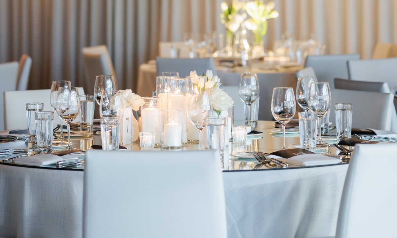 Table setting with wine glassware, candles, and white floral arrangements 