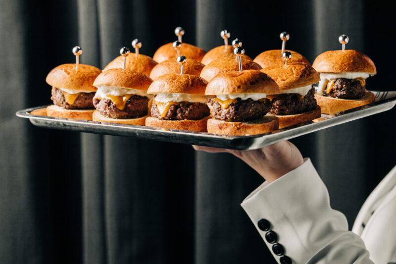 Mini dry-aged steak burgers on a tray.