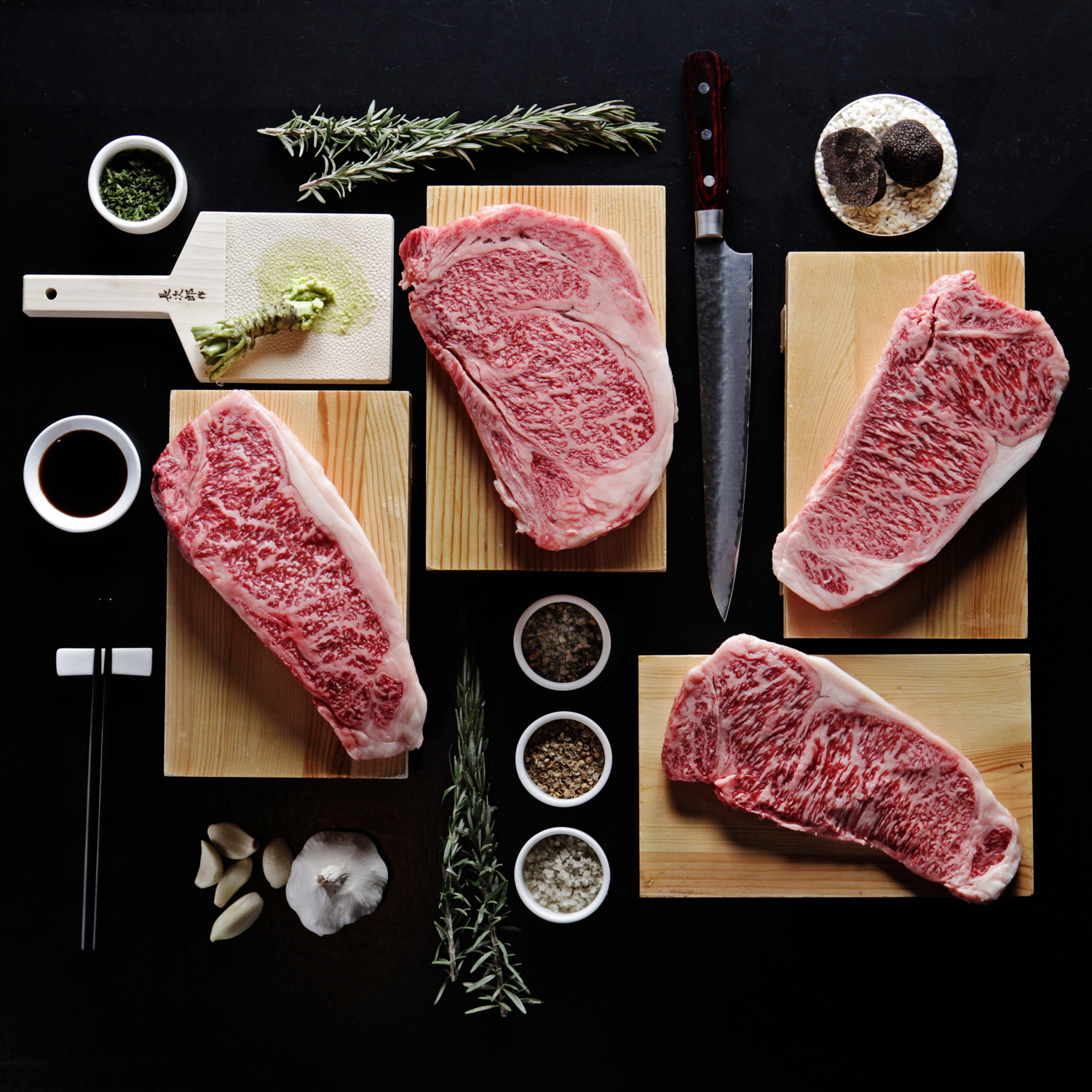 Raw steaks and ingredients like truffles, rosemary and salt 