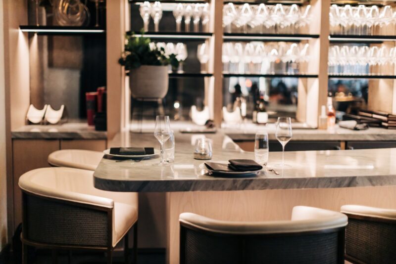 Sommelier station with place settings and shelf with wine glasses behind