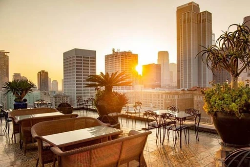 French-inspired rooftop bistro with unobstructed views of the downtown LA skyline.
Perch Los Angeles is a popular rooftop bar and bistro, located in downtown LA, surrounded with a magical view of Los Angeles skyscrapers and skyline, and the mountains in the distance.
Perch covers two floors, with a restaurant, bar & lounge on the 15th floor with both indoor and outdoor seating. And then there is the open-air rooftop terrace up on 16th floor.
The interior has a French bistro-feel with classy furniture and lush plants, and outside seating comes with a lot of cozy fireplaces and fire pits. On the restaurant level you can have both french inspired dinner and brunch on the weekends, preferably out on the patio.
Up at the top floor rooftop terrace only drinks are served, but these are on the other hand worth a visit in themself. Enjoy a wide selection of Parisian-inspired and crafted cocktails, as well as plenty of wine, beer and rare Cognacs.
Open nightly and from brunch-hour on weekends, Perch Rooftop Los Angeles comes with a pleasant and relaxed atmosphere, with a mixed crowd and often live DJs or jazz bands picking up the vibe even more. The prices are very reasonable, considering the setting, view and quality.
Do not miss the Perch rooftop bar Los Angeles if you if you wanna elevate yourself right in the middle of the City of Angels!
