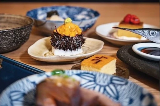 Right next to a railroad crossing, you’ll arrive at an unpretentious and minimalistic house. Immediately when entering OGAWA, you’ll feel as if you’ve landed in Japan.
Tucked away in Little River, Alvaro Perez has opened his fourth and newest Japanese restaurant that just earned a well-deserved Michelin Star.
As you turn the corner of the dining room, you will be met with the most impeccably set Omakase bar. Feel free to enjoy a pre-dinner drink in their peaceful Japanese garden in the back or take a seat, and get ready for Chef Masayuki and Chef Royce’s thoughtful Omakase journey.
At Ogawa intimacy and ‘kikubari’ (the Japanese art of caring for others) are valued at the highest level. This very personal dinner experience for 11 guests at a time focuses on seasonal and unique Japanese ingredients flown in daily. The first part consists of crudos with cooked dishes from the kitchen between each course. Next, you’ll move on to the most incredible sushi flight, followed by a miso soup, and finish off with desserts (that’s not a typo, there’s more than one).
Our favorite dishes when we went included the best Hotate Nigiri we’ve seriously ever had, balanced with a touch of Key lime and salt (we literally won’t shut up about it); the Ensui Hokkaido Uni Gunkanmaki which is preserved in salt water so you can taste the Uni right from its natural habitat; the Uni and Ikura Hand Roll; and a special shout out to the Matcha Mochi Cookie Anko with Satsumaimo (Japanese sweet potato) Ice Cream by Chef Jamie, picture your childhood Whoopie Pie but soooooo much better.