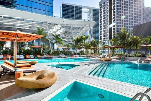 EAST Miami
On the top and 40th floor of EAST Miami you find the highest rooftop bar in the city, called Sugar. And while the hotel's rooftop pool is not as high, it still offers an impressive setting.
Found on the 5th floor, the Pool & Deck is a tropical oasis for guests staying at the hotel from sunrise to sunset. Equipped with several small pools and one larger, comfy sunbeds and orange umbrellas, the terrace is a perfect spot to enjoy relaxing Miami days.
Apart from getting some well-deserved rest under a palm tree, you can also indulge in a menu filled with refreshing beverages and tantalizing snacks from the signature eatery Quinto La Huella.