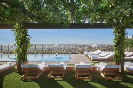 The West Hollywood EDITION
The sleek and modern place offers a truly beautiful LA rooftop oasis. At The Roof rooftop bar, but maybe even more so at the rooftop pool deck.
Perched above Sunset Boulevard and with amazing views of the Hollywood Hills, Beverly Hills and the iconic LA skyline, here guests staying at the hotel can soak up the sun and enjoy refreshing swims elevated high above the city.
Surrounded with lush botanicals, mature trees and terra cotta-potted plants, as well as bespoke wooden loungers, the rooftop pool deck is the perfect spot to catch the sunrise, sunset and everything in between.