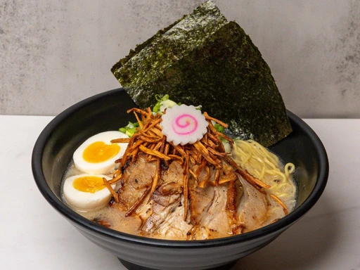 Dinner at Shimuja Ramen
This Friday, July 26, find us slurping away at Shimuja Ramen, a beloved South Florida gem.
Since opening its doors in Miami in 2018, Shimuja Ramen has quickly become a local favorite, earning the title of “Best Ramen Shop in Miami 2024” from The Miami New Times. Originally founded in Kagoshima City, Japan, in 2011, Shimuja Ramen brings its rich heritage to Miami through the culinary artistry of Chef and Owner Keiichi Maemura.
Chef Maemura’s meticulous 13-hour pork-bone broth forms the heart of an extensive ramen menu that includes delicious vegetarian options. Shimuja Ramen is known for its richly flavored broths and fresh ingredients. Their standout dish, the Kagoshima Special, is a delightful combination of smoked pork belly, mixed vegetables, scallions, naruto, fried burdock, a soft-boiled egg, and thick wavy noodles. Other favorites like the Satsuma Tonkotsu and Tokyo Shoyu offer a more classic approach to authentic flavors straight from Japan. Don’t miss out on the quintessential Florida ramen either — the Key Lime, prepared with chicken slices, key lime juice, lettuce, red onion, scallion, thin straight noodles, and half soft boiled egg.