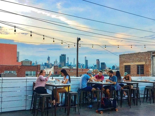 A large rooftop located right next to McCarren Park in Brooklyn, Berry Park is a fantastic sports bar with even better city views. From up here, you can enjoy the Manhattan skyline and Brooklyn's rooftops while watching the big game, as Berry Park is best described as a soccer bar and beer garden.
As that description implies, beers are the most popular drink in Berry Park, and you can find a vast variety of them, with German and Belgian beers at the forefront. If beer isn't your thing, you can always enjoy wines, spirits, and a handful of signature cocktails.
Food-wise, expect to find bratwurst, fries, and other dishes with German influences, as well as a choice of American pub classics. There's also a brunch menu, which you can enjoy every weekend.
While the weekend nights at Berry Park might be a bit to vibrant to bring kids, other times it is a great option for a family looking to mix pub-grub and views. Especially the soccer interested family, as the rooftop opens early for Champions League and Premier League games.