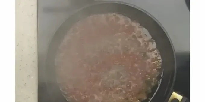 Pour the grated pulp of the tomato into a heated frying pan with oil.
