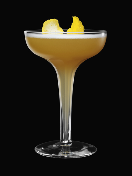 The First Word: a rusty orange coloured drink served in a coupette glass, garnished with lemon peel