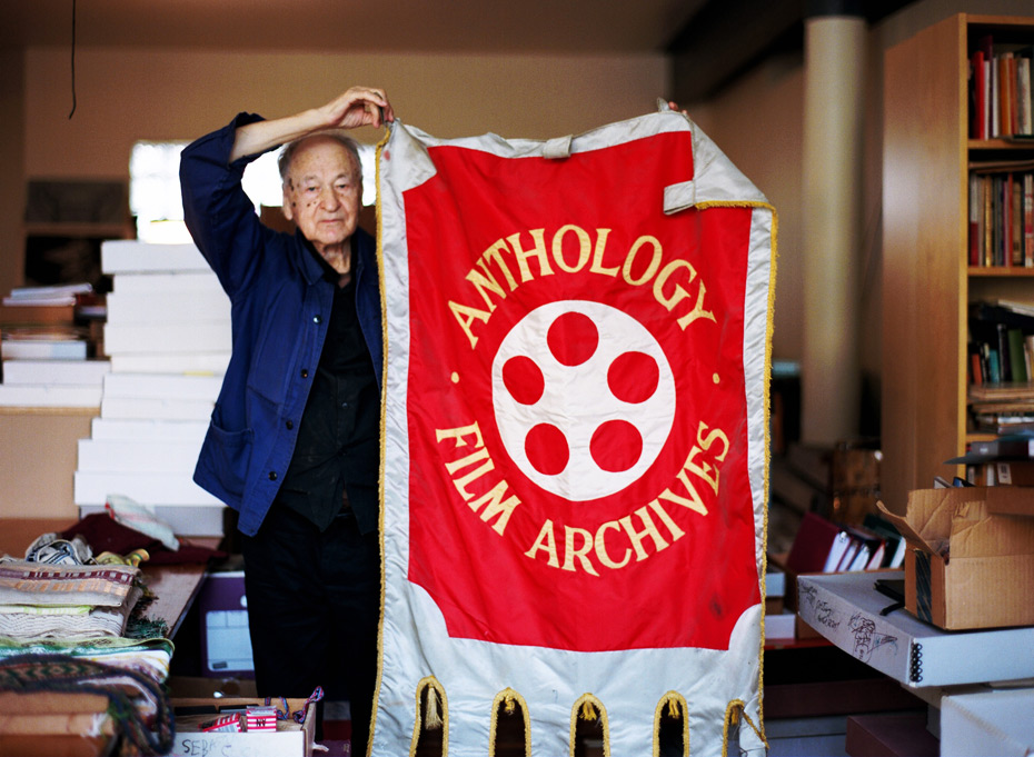 Jonas-Mekas-holding his AFA banner in his studio