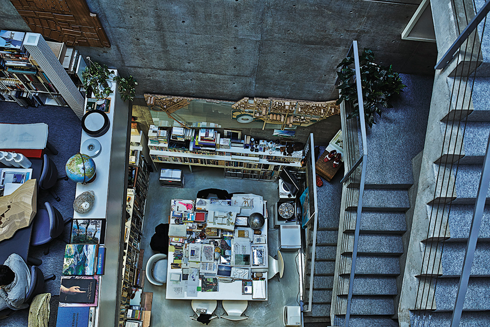 Ando’s desk is surrounded by shelves and covered with books, sketches and models