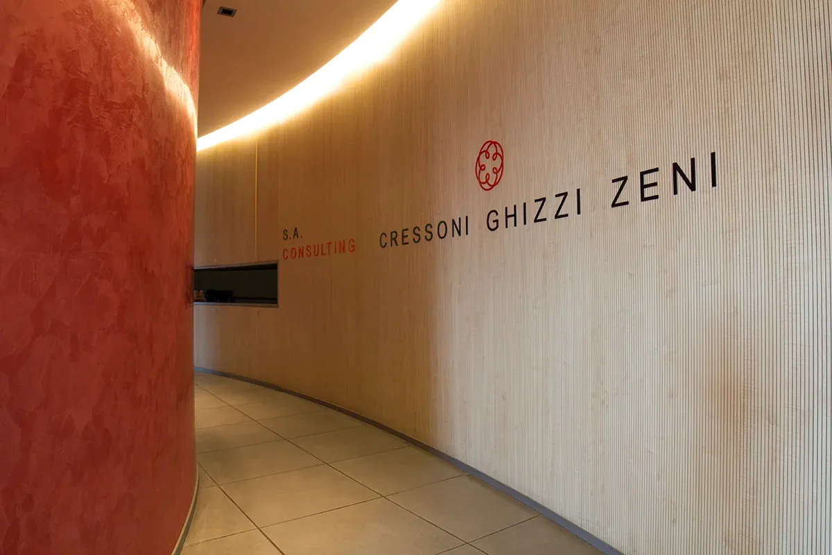 Corridoio curvo con logo aziendale e pareti in legno chiaro e rosso.