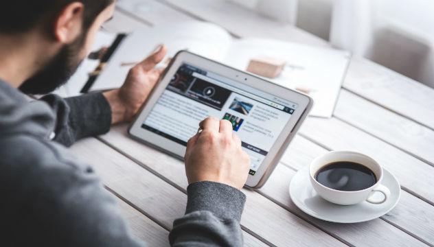 man working on a tablet computer with a cup of coffee