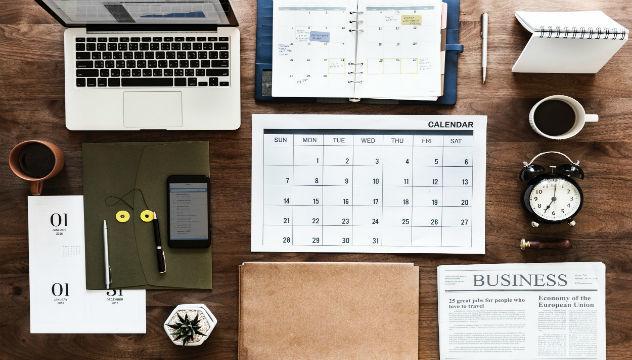 diary, folder, newspaper, laptop etc organised on a desk