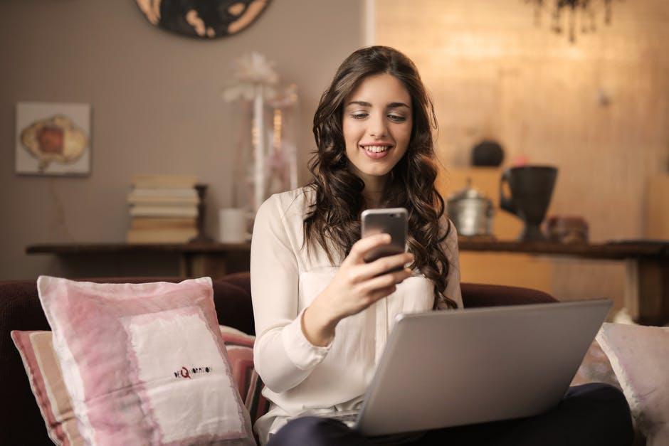 woman using a mobile phone and laptop