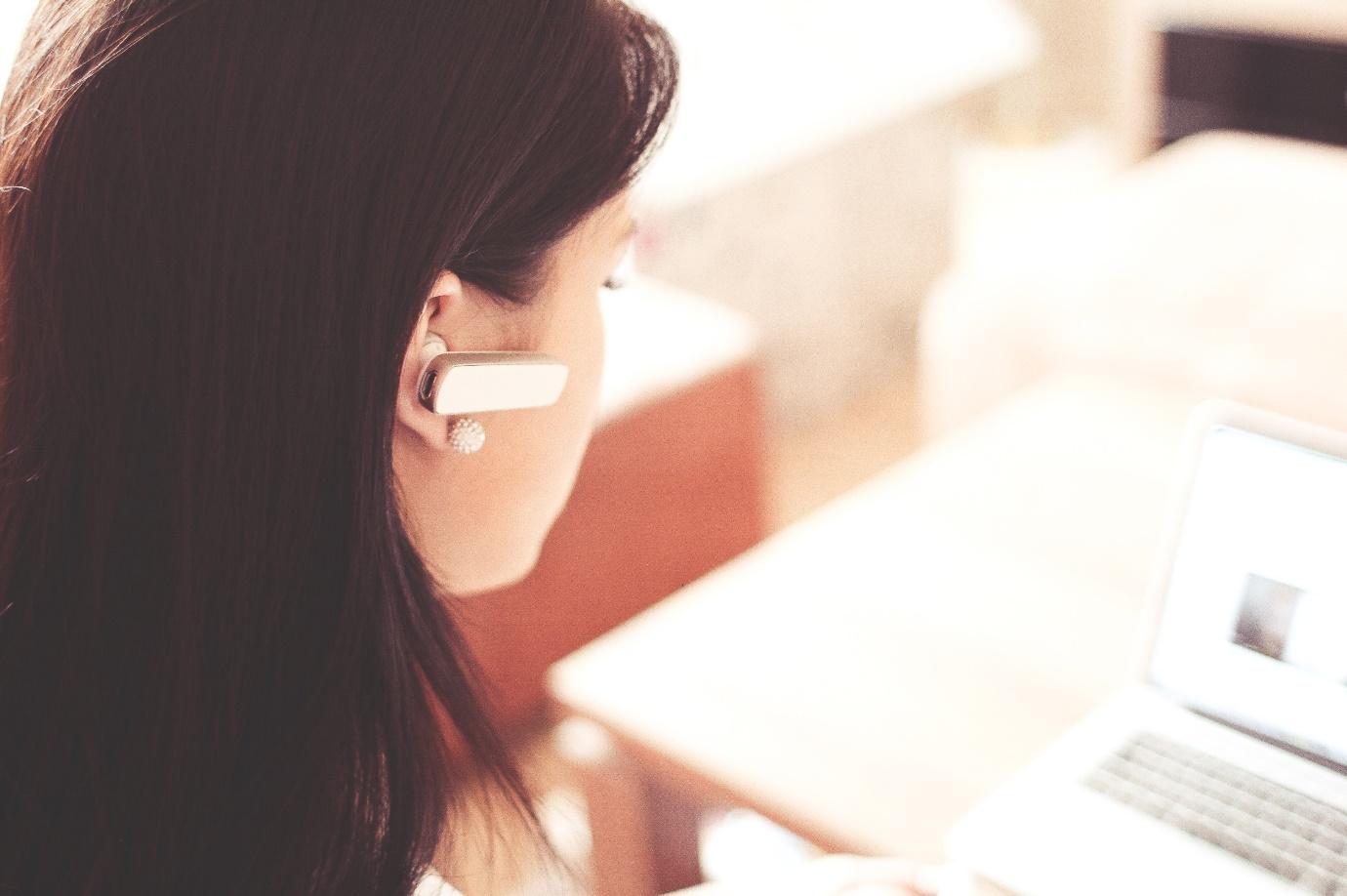 Woman on a Laptop With an Earpiece Representing Offline Marketing