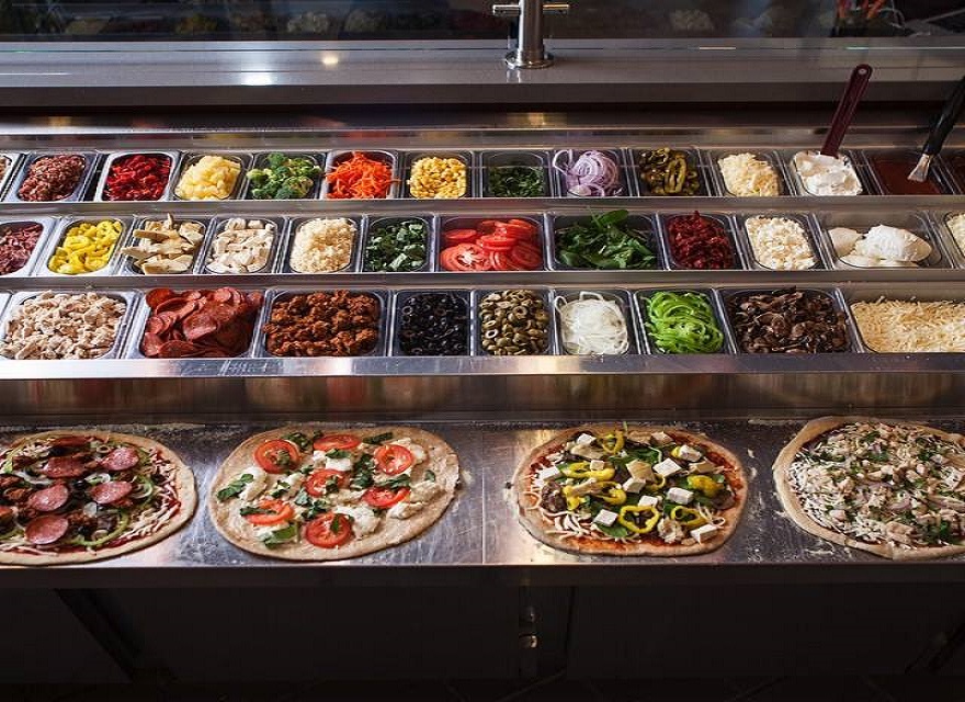 Variety of Pizza Toppings and 4 Pizzas Ready to Go in the Oven Below