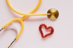 Free Stethoscope near decorative coil tie in heart shape on pink surface Stock Photo