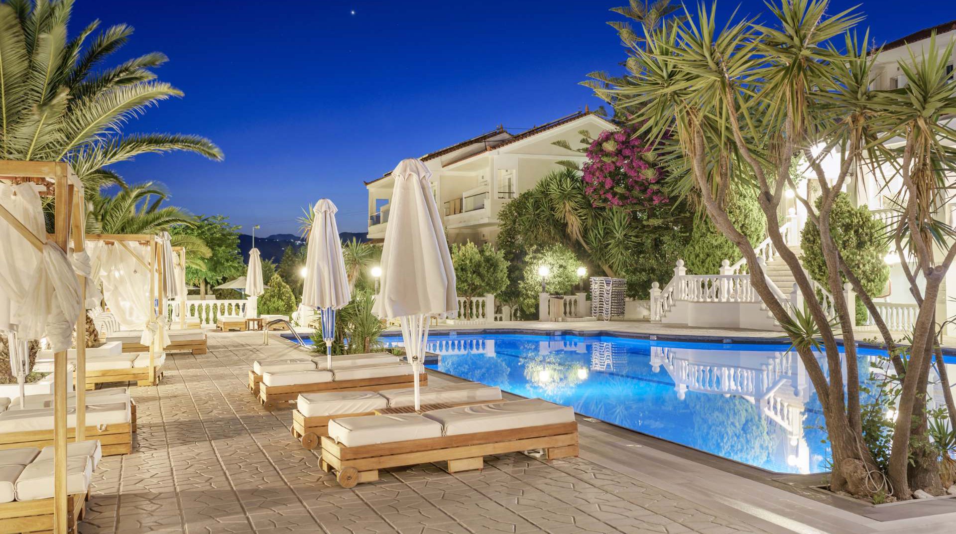 Our pool during night time with the deck chairs and the trees