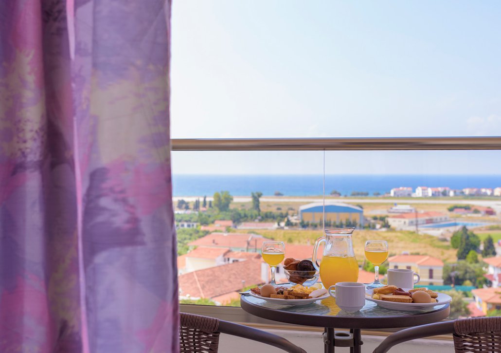 Table at the balcony of our room with plates full of our delicious breakfast and juice looking at the sea