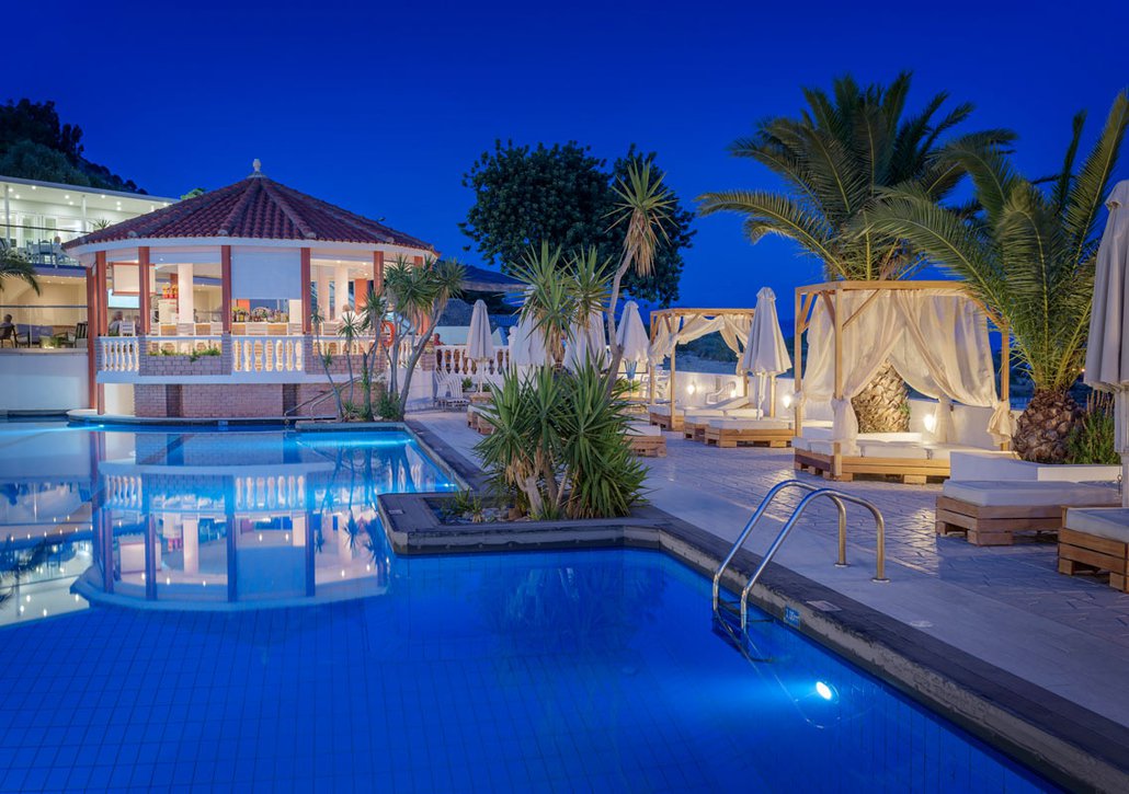 Our pool during night time with the deck chairs and the trees