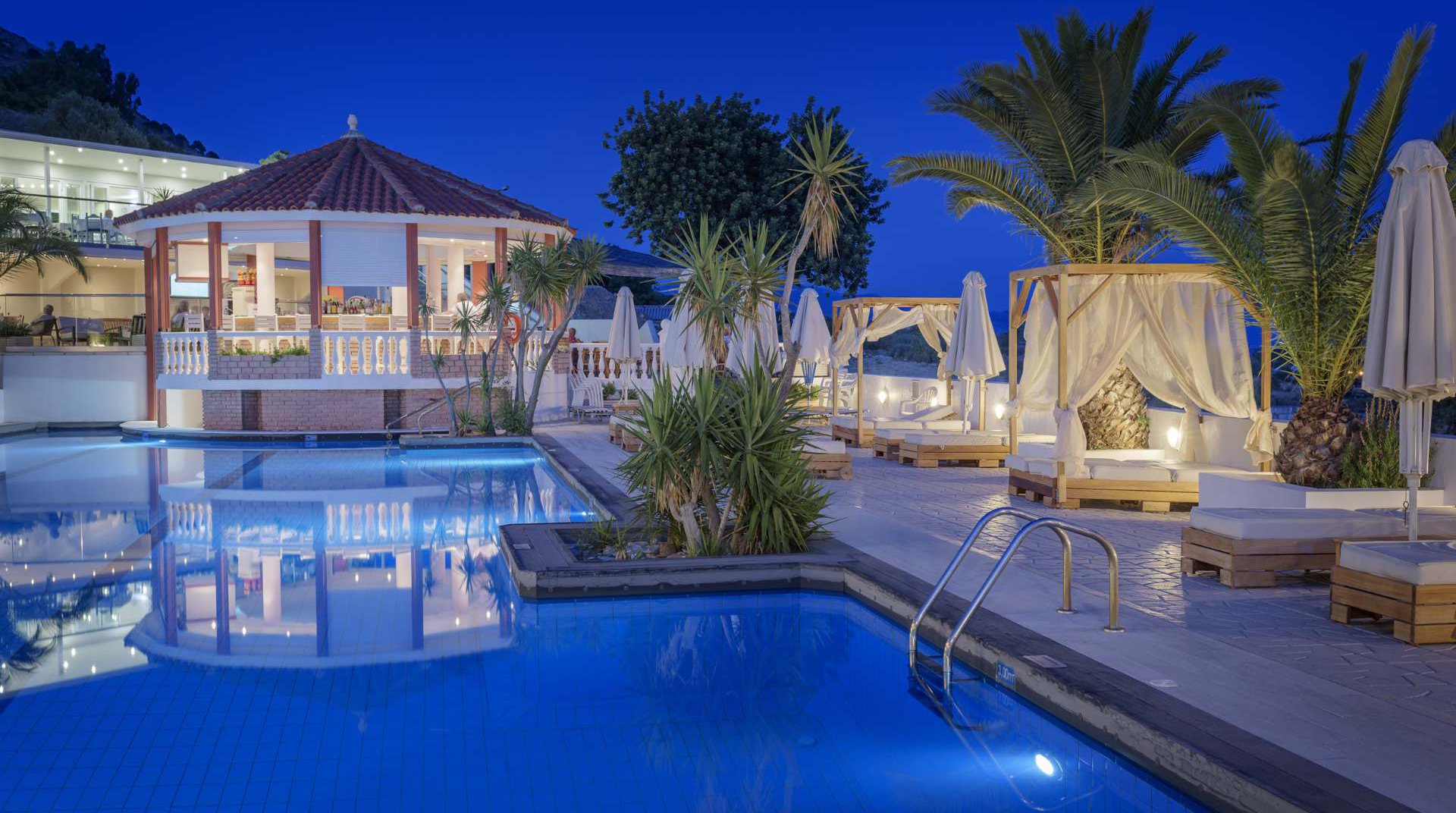 Our pool during night time with the deck chairs and the trees