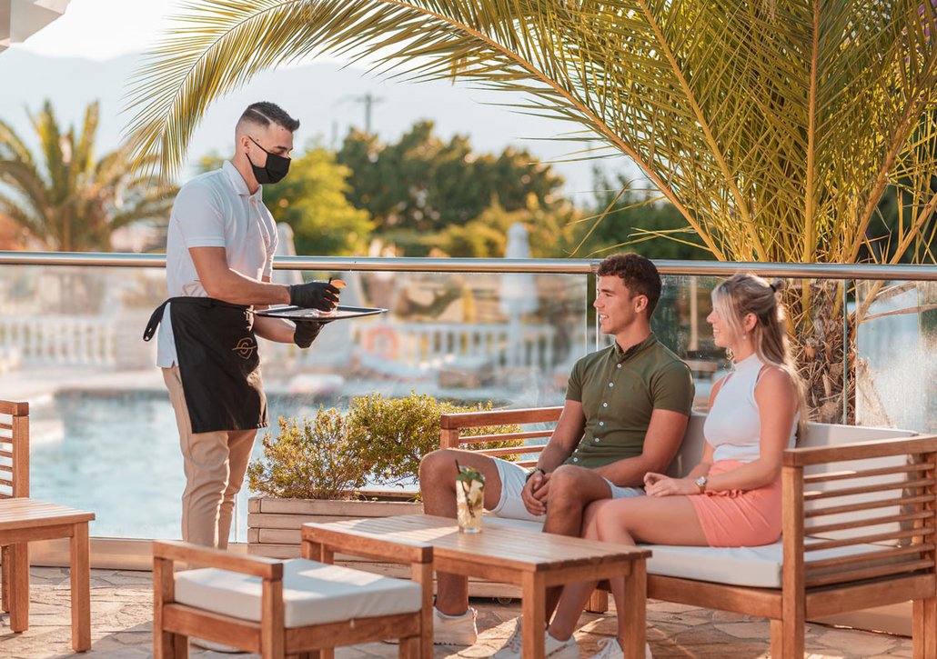 Waiter serving customers wearing mask and gloves