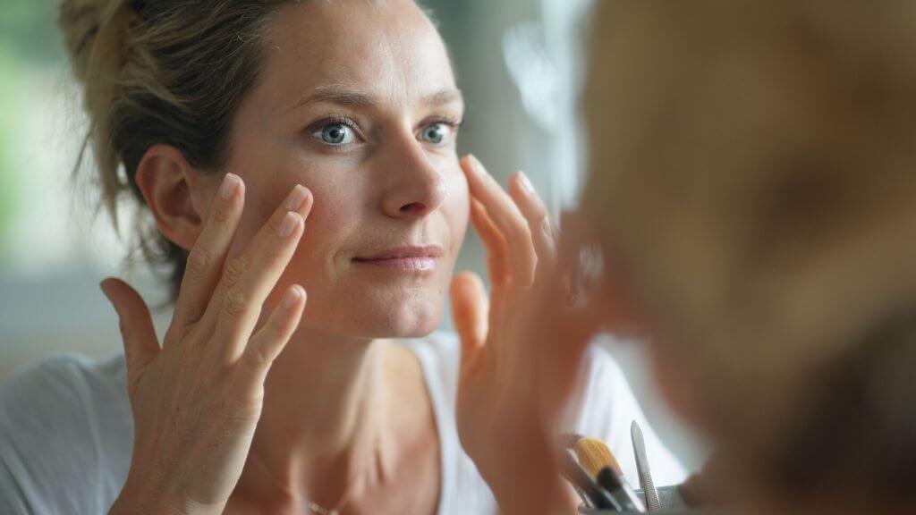 A woman applying toner to her face.