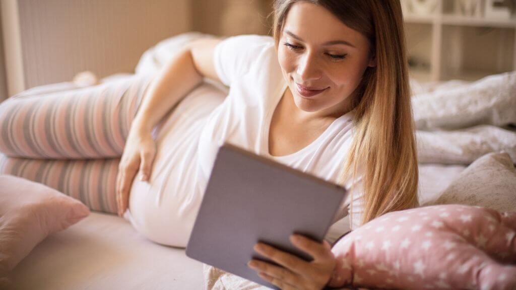 A pregnant woman reading her tablet device