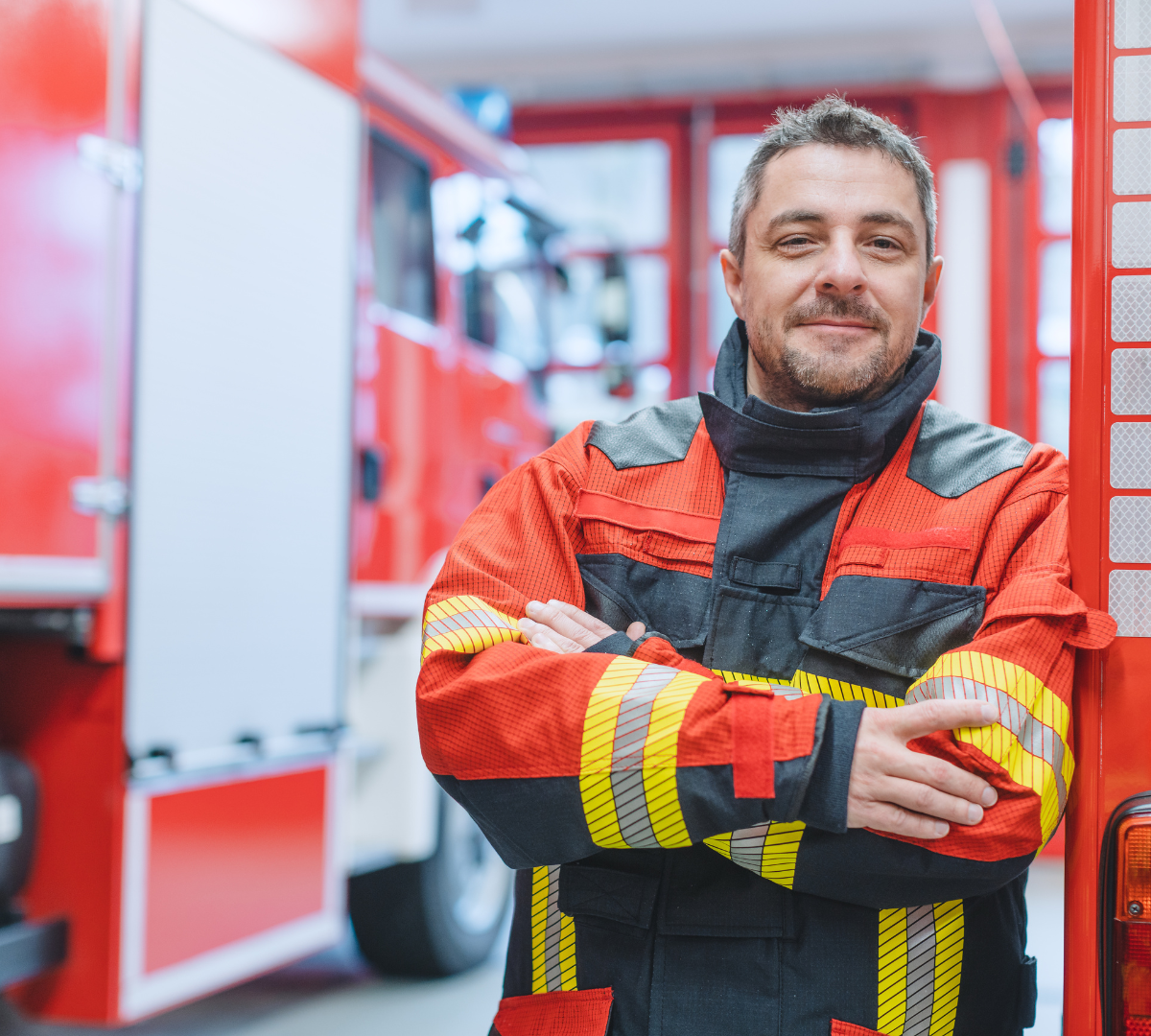 fire fighter man standing in front of fire truck with arms crossed