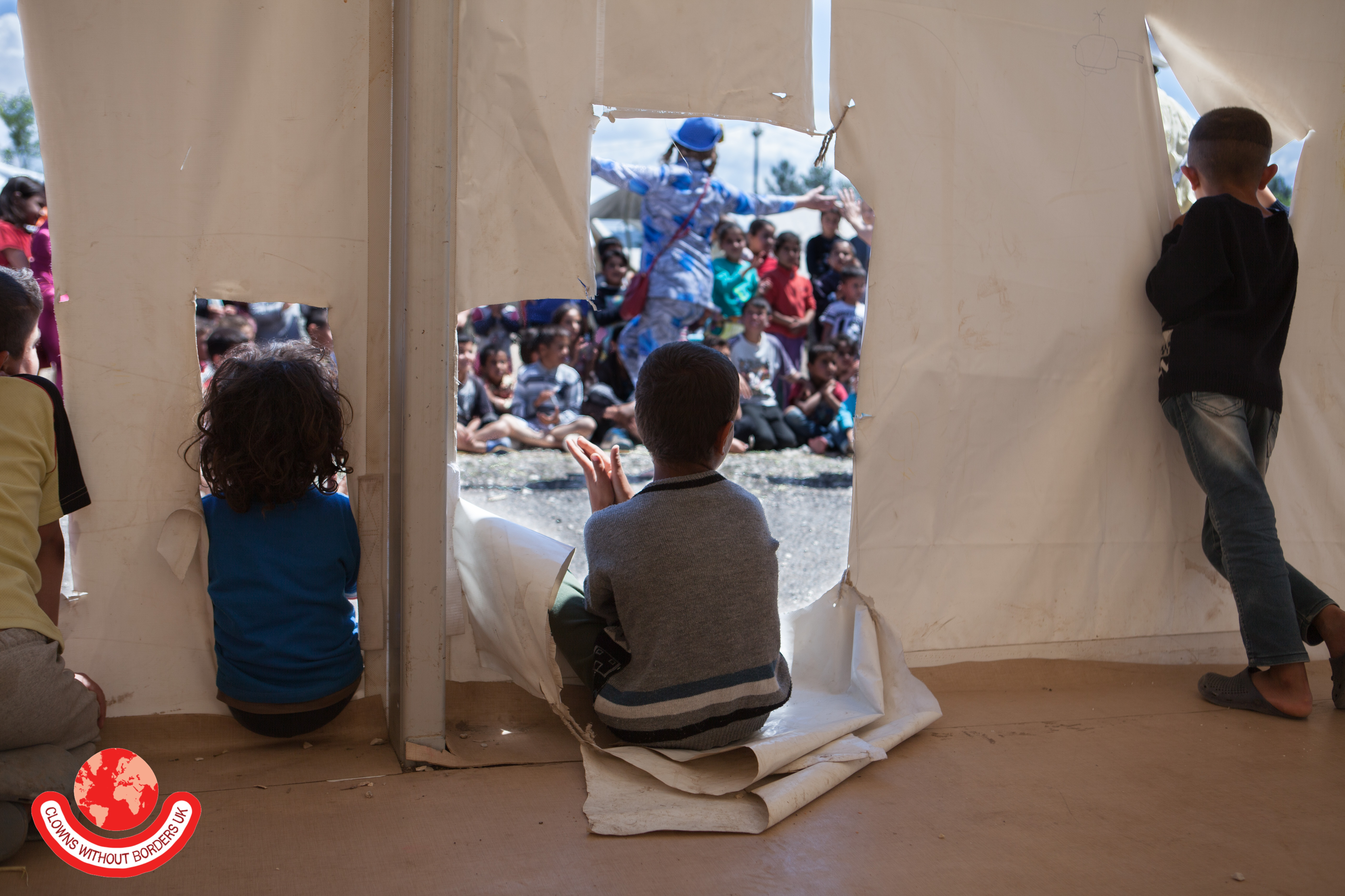 Children watching clown performance through a tent