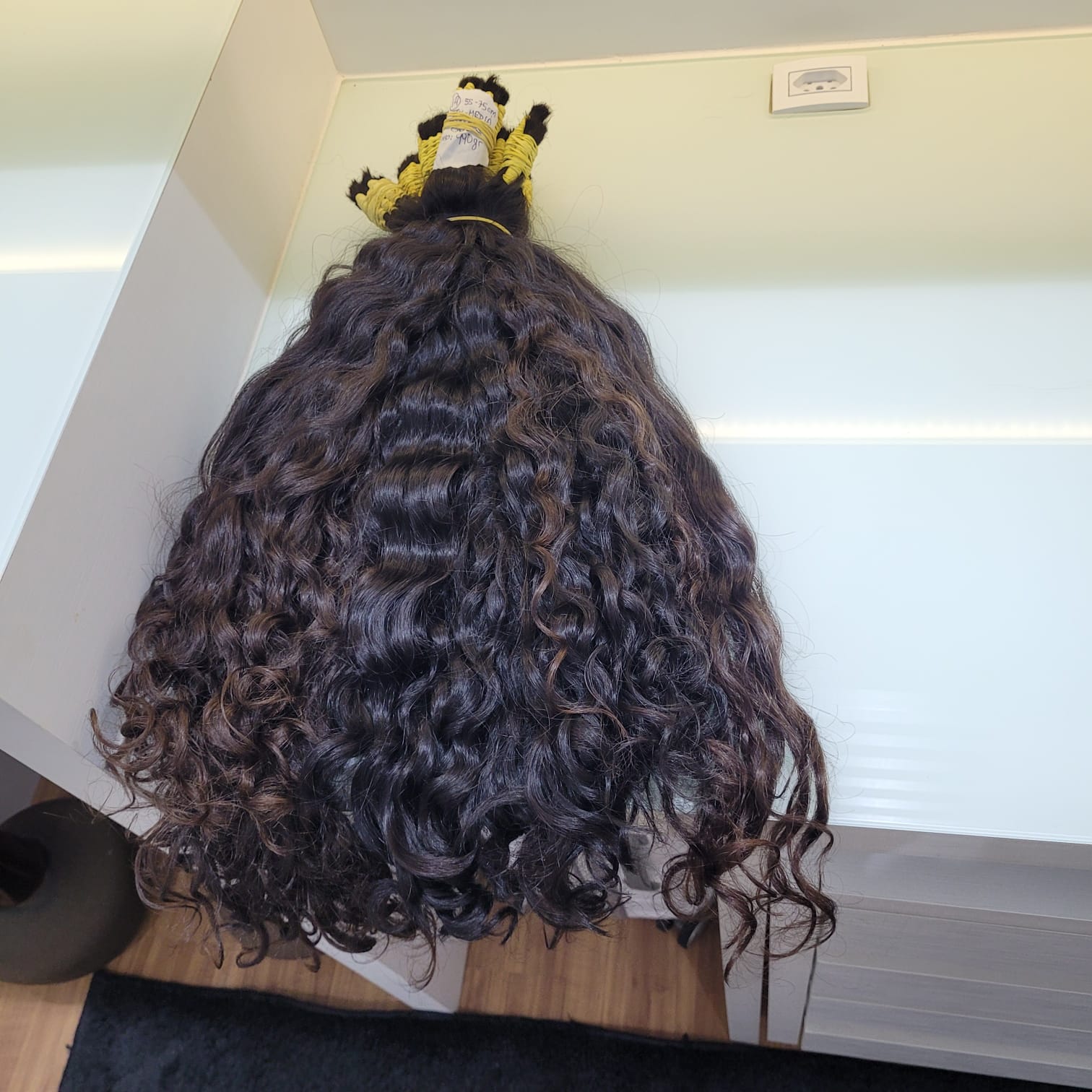 A woman getting curly hair extensions installed