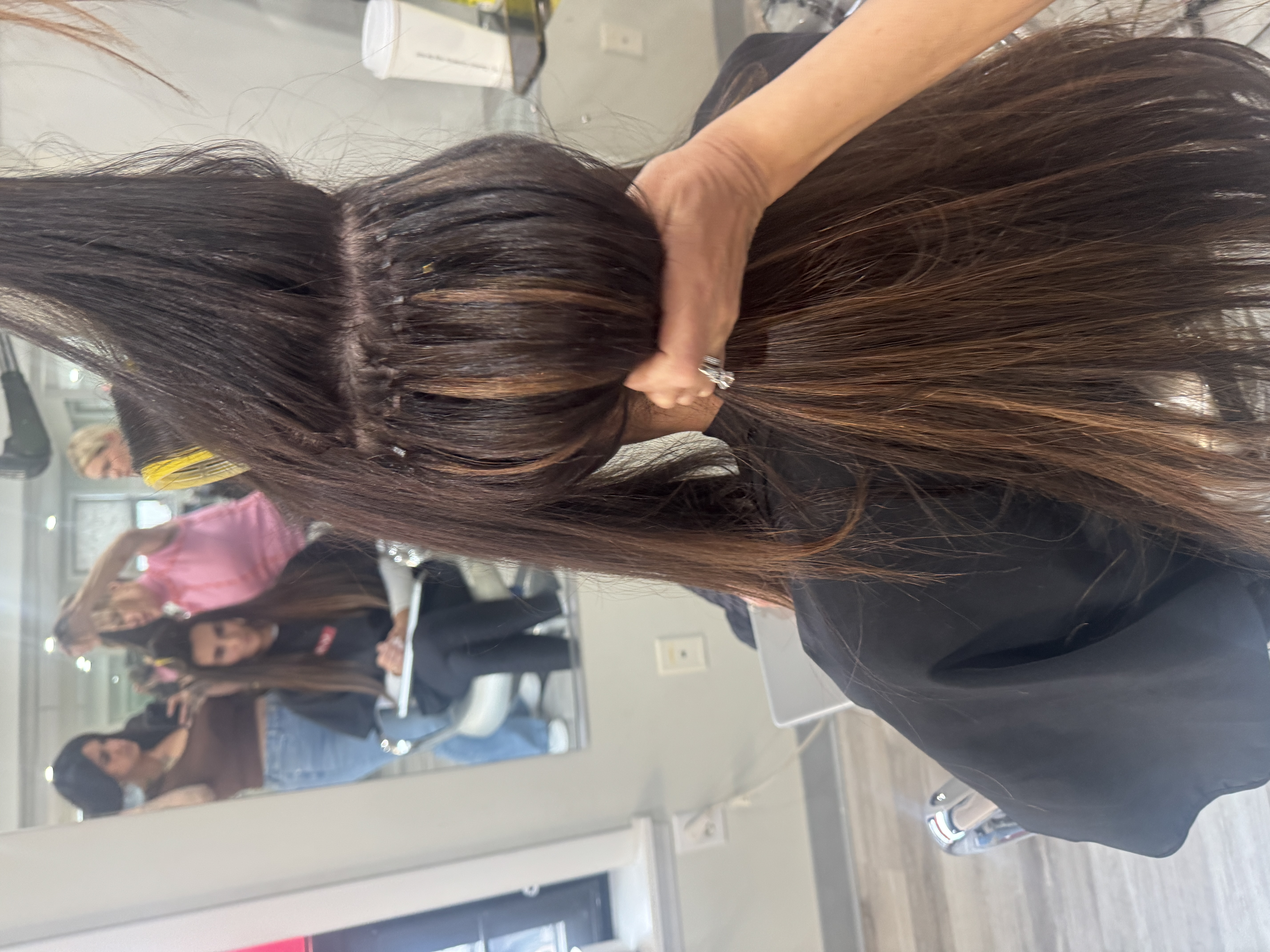 A woman getting micro link hair extensions attached