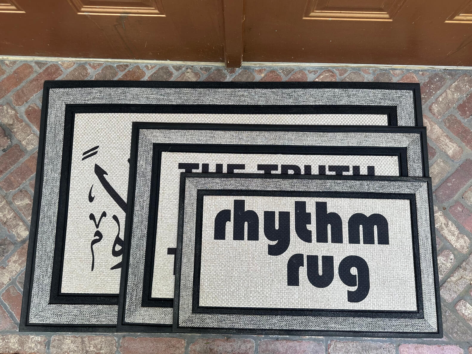 3 sizes of all weather mats in a stack on a brick porch