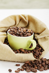 Image showing Green cup filled with coffee beans in bag