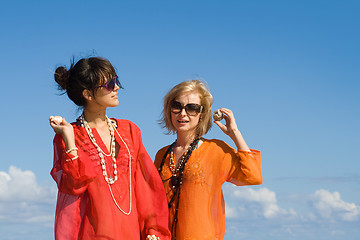 Image showing two beautiful women hearing shells on beach