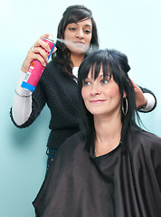 Image showing Hair stylist sprays customer's hair