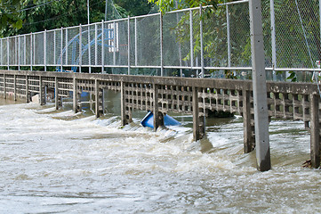 Image showing Water flowing through a broken fence during a flood
