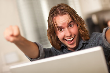 Image showing Cheering Young Man Using Laptop Computer
