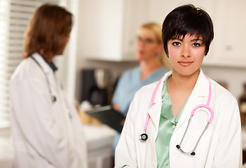 Image showing Pretty Latino Doctor Smiles at Camera as Colleagues Talk