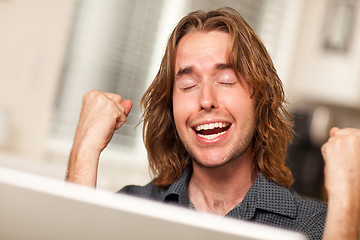 Image showing Cheering Young Man Using Laptop Computer