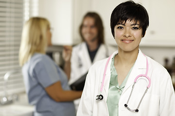 Image showing Pretty Doctor Smiles at Camera as Colleagues Talk