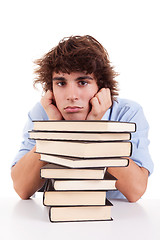 Image showing cute boy bored, among books, on his desk