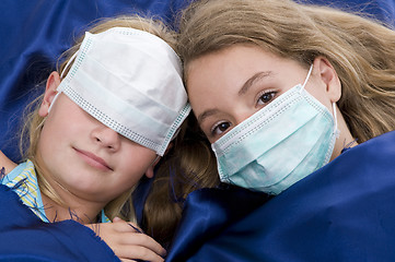 Image showing sisters in bed with protective mask