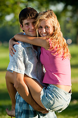 Image showing A couple of lovers - a young man holding a girl on his hands in 