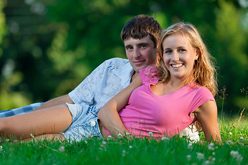 Image showing A couple relaxing in the park, lying on the grass, lit in the ev