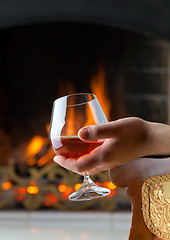 Image showing Resting at the burning fireplace fire with a glass of cognac