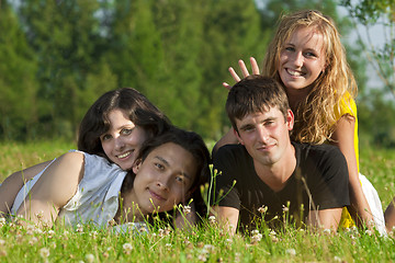 Image showing Four young men - two girls and two guys lying on the grass in th