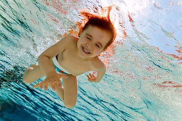 Image showing The girl smiles, swimming under water in the pool