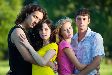 Image showing Four young people embrace and stand in the park