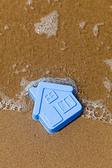 Image showing Plastic toy house lies on the sand